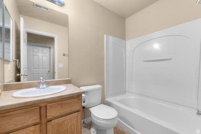 3053 Sage Loop, Unit B1 Lehi, UT 84043 - Photo 16 of 25 Full bathroom featuring a single vanity with wood cabinetry and a laminate countertop, an oval undermount sink, and a combination shower-tub with a white surround