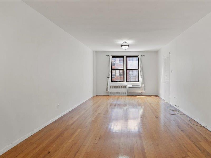 665 Thwaites Place, Unit 3N Bronx, NY 10467 - Photo 4 of 10 an empty room with wooden floor and windows
