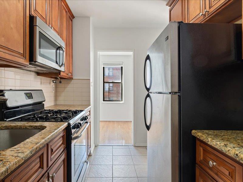 665 Thwaites Place, Unit 3N Bronx, NY 10467 - Photo 6 of 10 a kitchen with stainless steel appliances granite countertop a stove a refrigerator and a microwave
