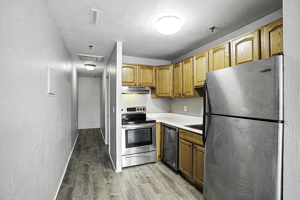 531 Main Street, Unit 410M Worcester, MA 01608 - Photo 5 of 29 a kitchen with a refrigerator a stove top oven and cabinets