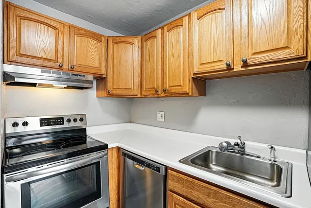 a kitchen with stainless steel appliances granite countertop a refrigerator a sink and a stove
