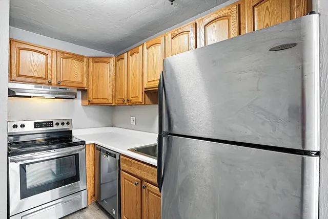 a view of kitchen and empty room with wooden floor