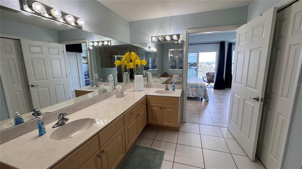 13999 Gulf Boulevard, Unit 501 Madeira Beach, FL 33708 - Photo 31 of 58 a bathroom with a double vanity sink and a mirror