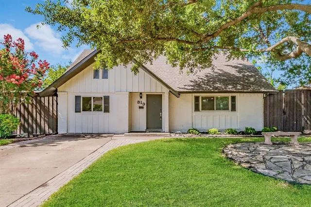 a front view of a house with a garden and trees