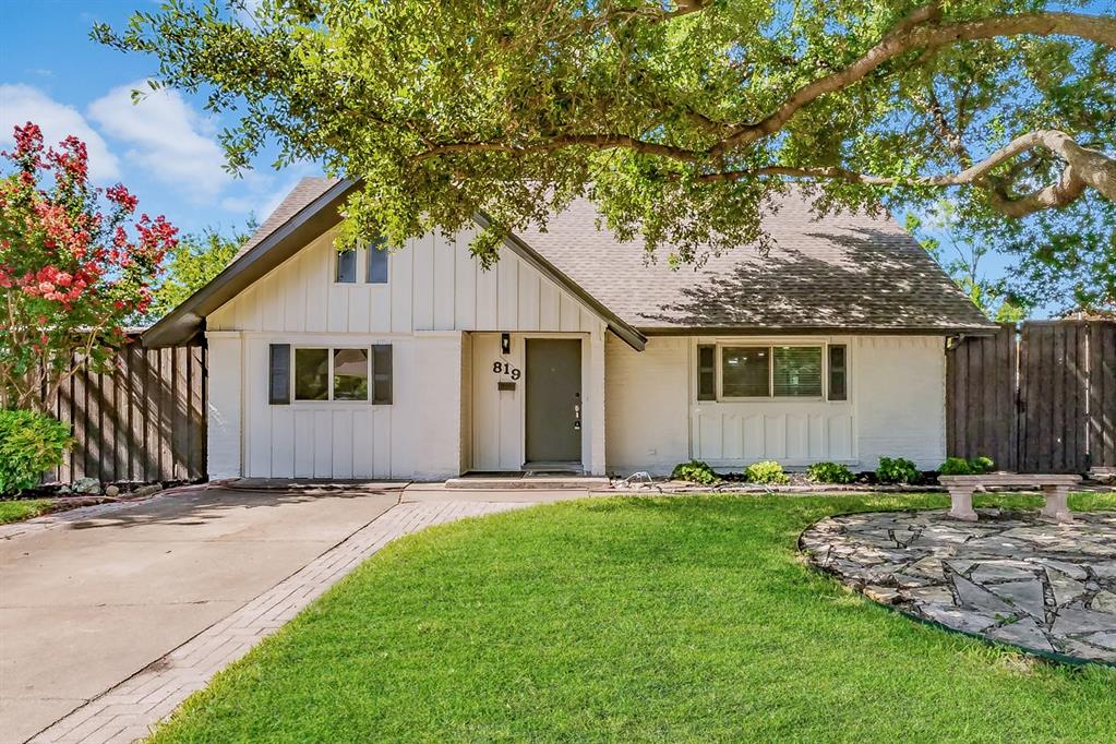 a front view of a house with a garden and trees