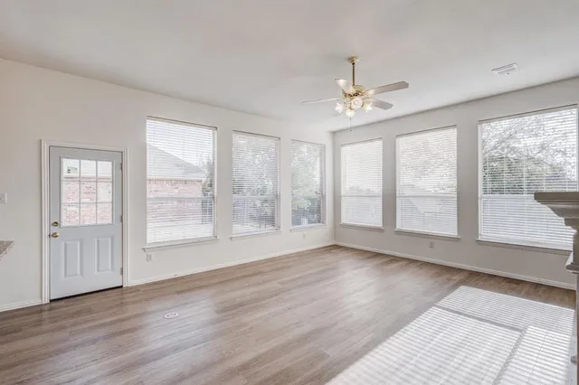 a view of an empty room with a window and wooden floor