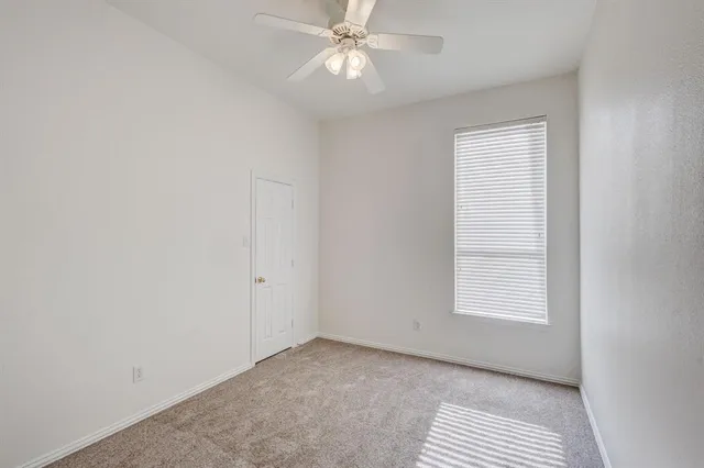 an empty room with chandelier fan and windows