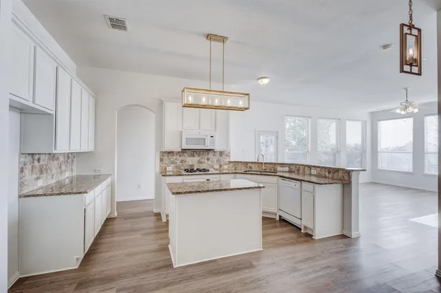 a kitchen with stainless steel appliances granite countertop wooden floors and white cabinets