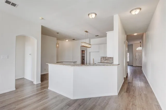 a living room with kitchen island wooden floor and refrigerator