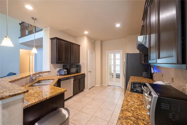 a kitchen with granite countertop kitchen island stainless steel appliances a sink stove and cabinets