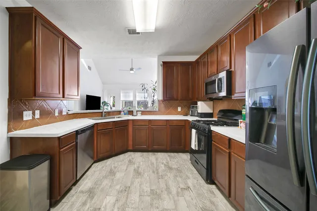 a kitchen with stainless steel appliances granite countertop a sink refrigerator and cabinets