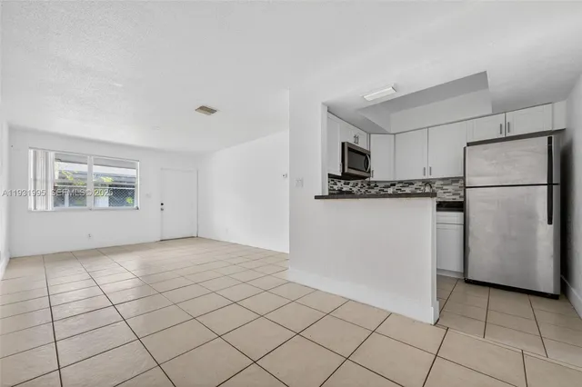 a kitchen with white cabinets and refrigerator