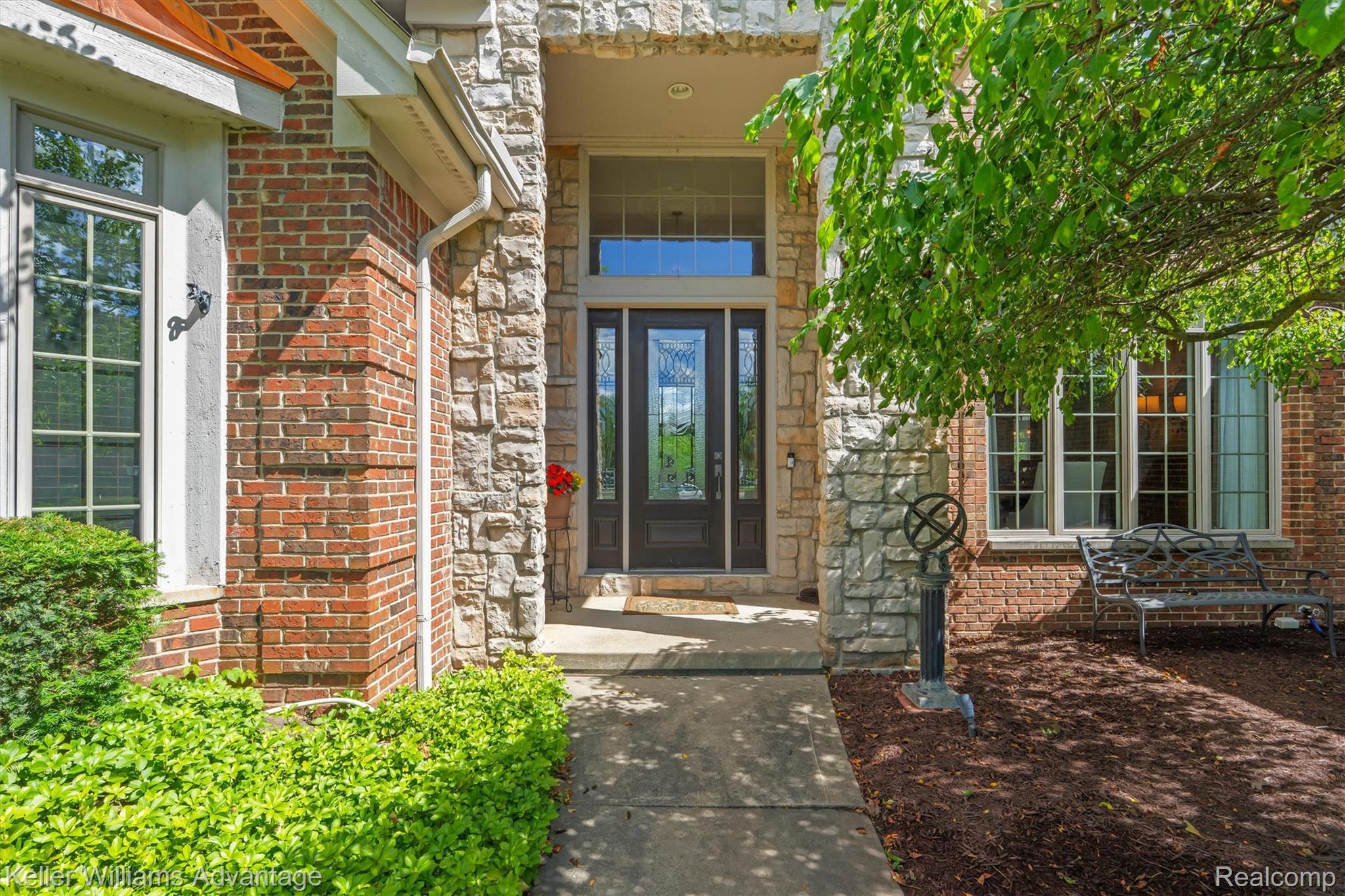 22878 Tree Top Court South Lyon, MI 48178 - Photo 2 of 75 Stone and brick facade with a prominent entry featuring a dark wood door with decorative glass inserts