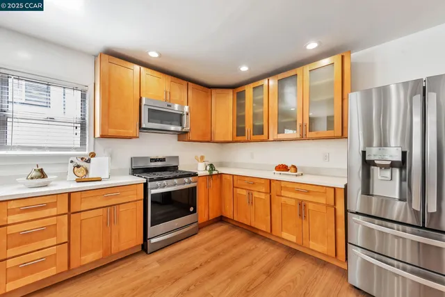 a kitchen with stainless steel appliances granite countertop a stove top oven a sink dishwasher and a refrigerator with wooden floor