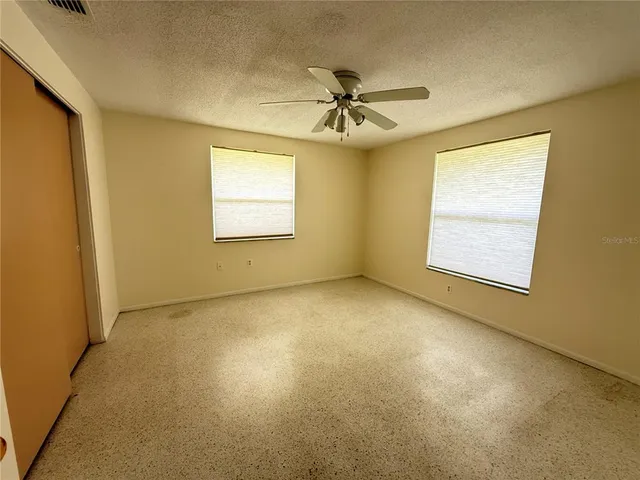 an empty room with a ceiling fan and a window