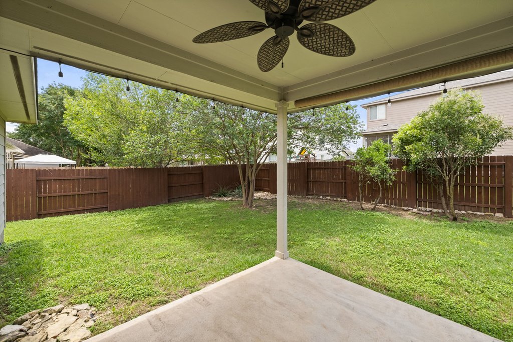 347 Spring Drive Kyle, TX 78640 - Photo 35 of 40 A spacious backyard with mature trees, verdant grass, and a welcoming covered patio.