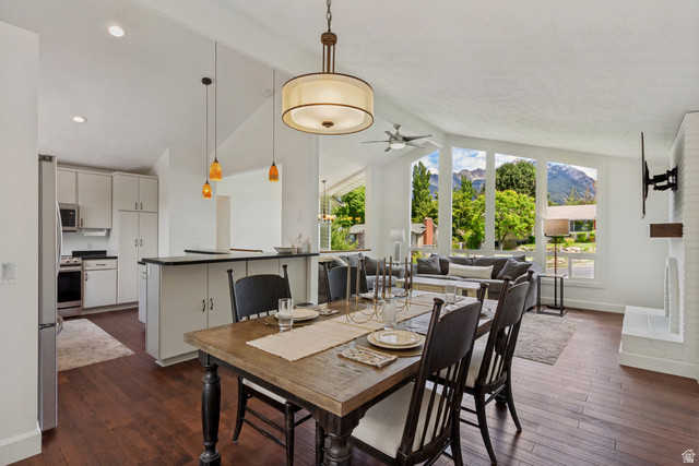 9706 Raintree Drive Sandy, UT 84092 - Photo 9 of 42 Open-concept living space featuring wood-finish flooring, a white brick fireplace, vaulted ceilings, and large windows with mountain scenery