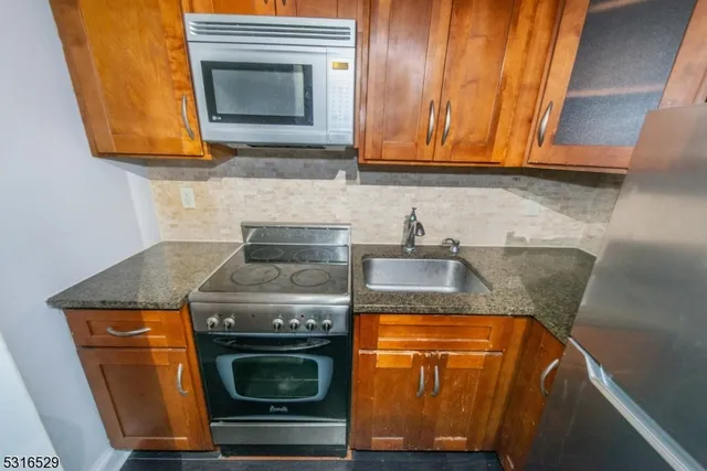 a kitchen with granite countertop wood cabinets and a stove top oven