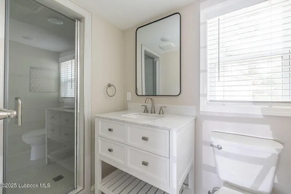 a bathroom with a granite countertop toilet a sink and a window