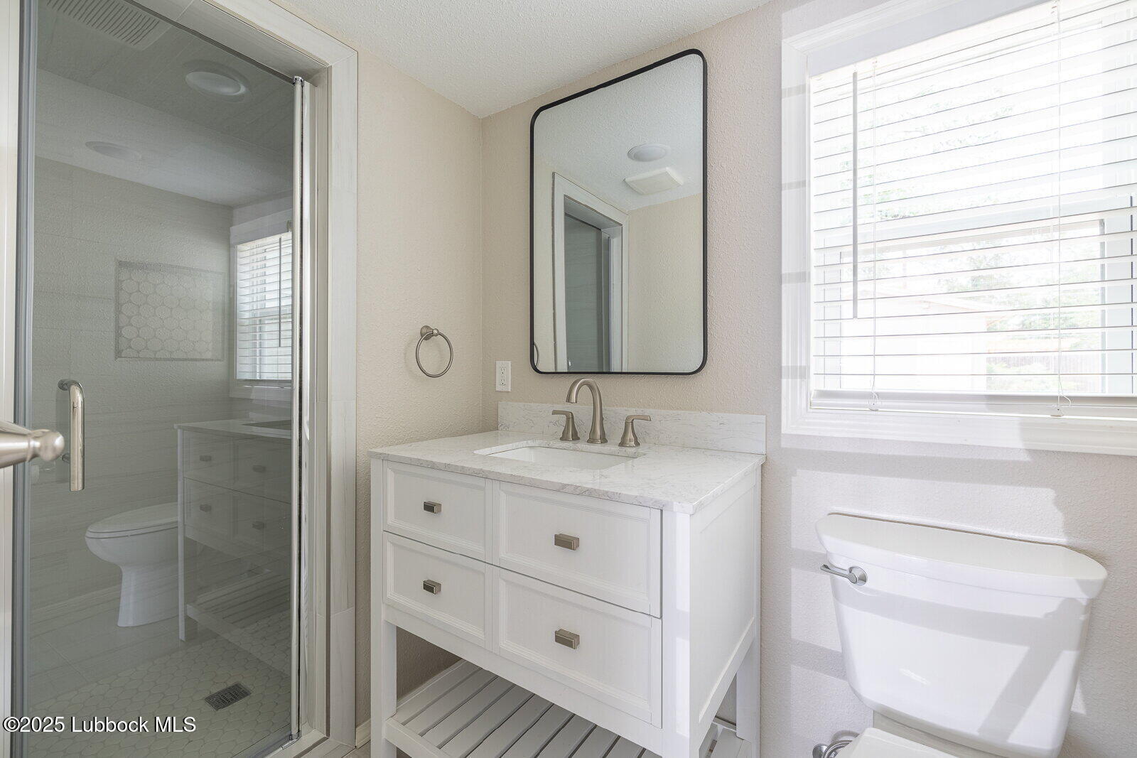2614 24th Street Lubbock, TX 79410 - Photo 18 of 46 a bathroom with a granite countertop sink a toilet a mirror and shower