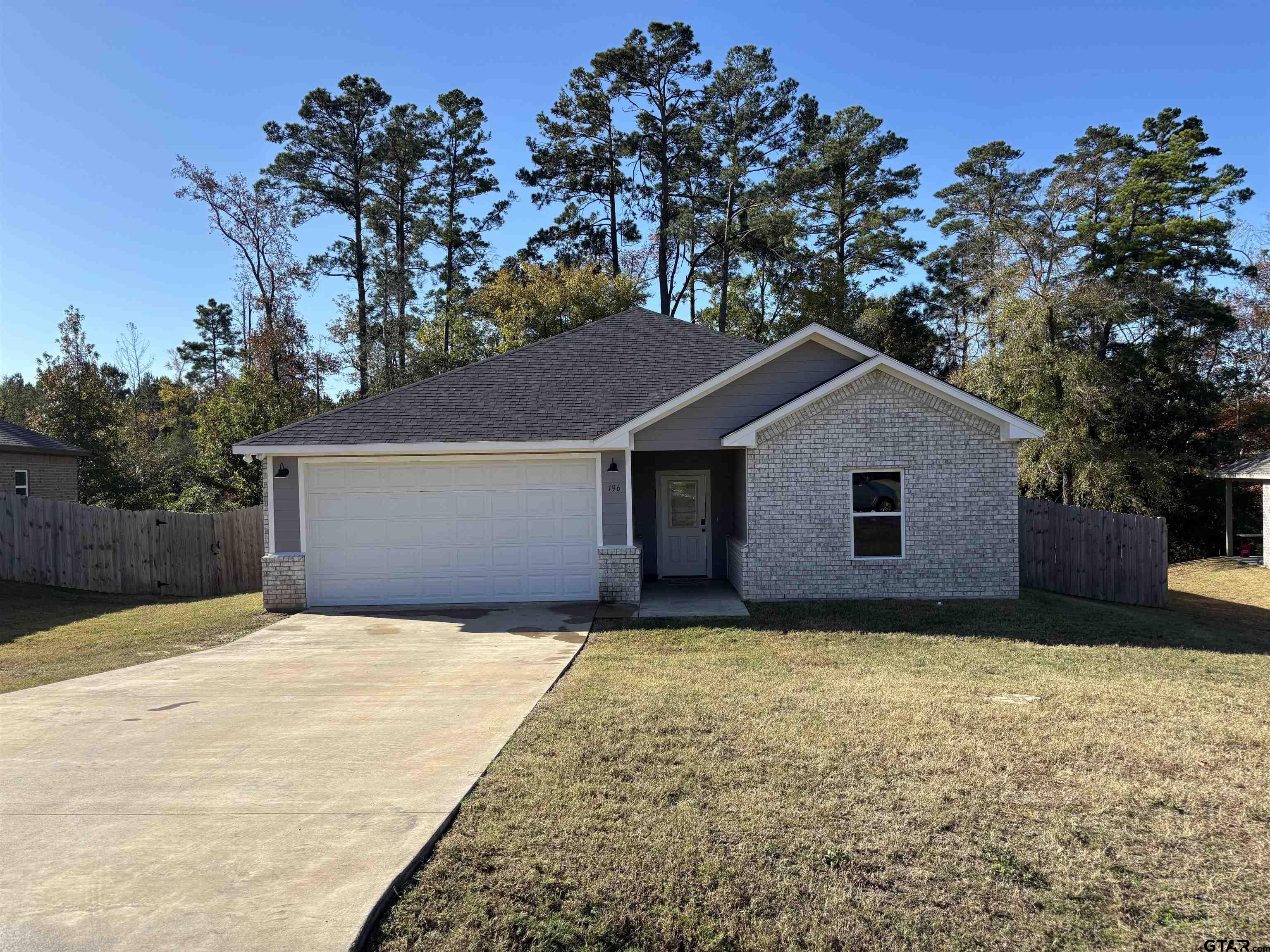 a front view of house with yard and trees in the background