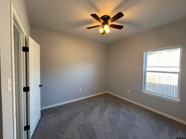 an empty room with windows and chandelier fan