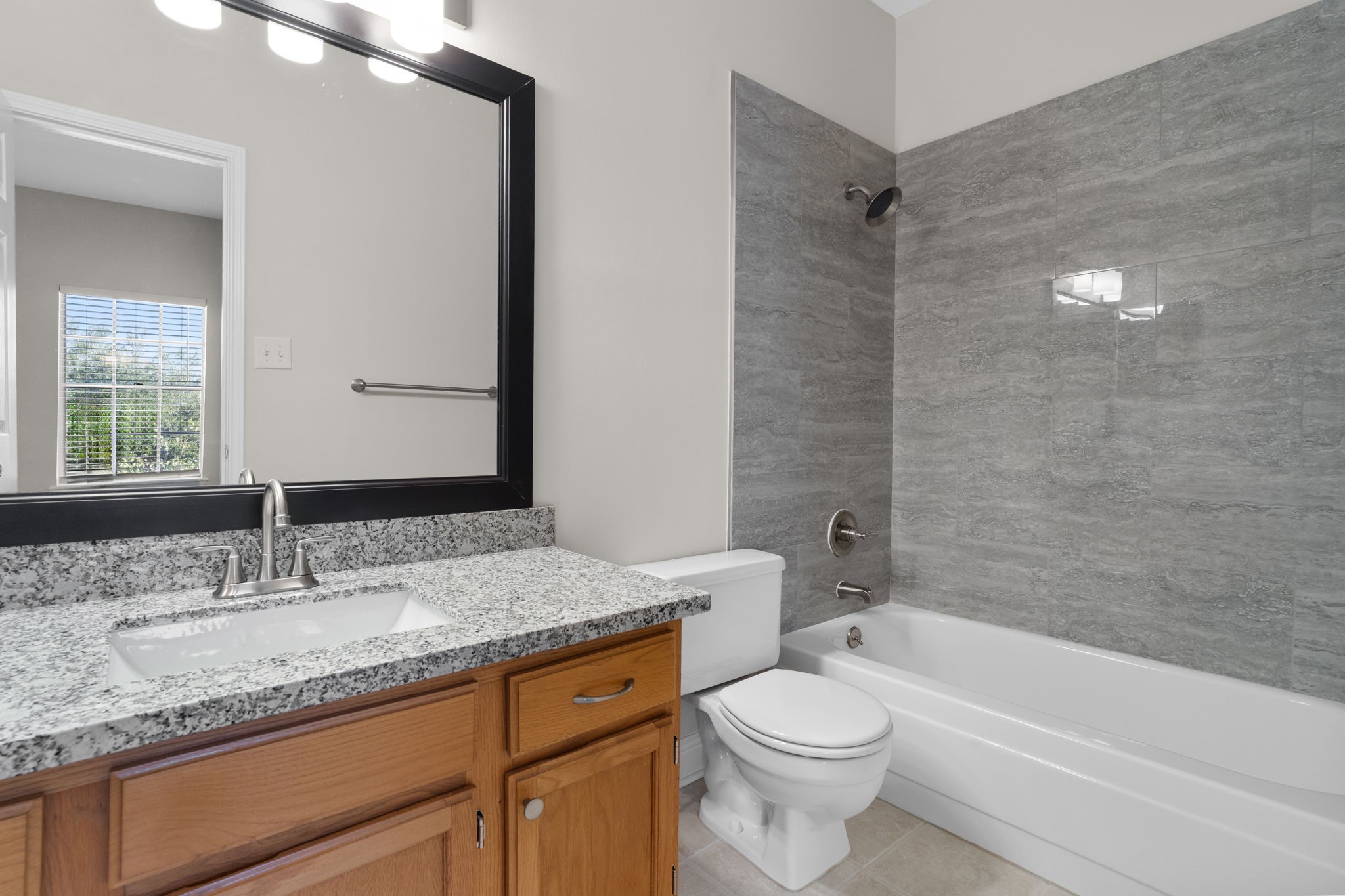 7392 Regency Square Court, Unit 7392 Houston, TX 77036 - Photo 25 of 32 En suite bathroom shower/tub combo is surrounded by stylish, trend-conscious tile, paired with an updated granite countertop and contemporary fixtures.