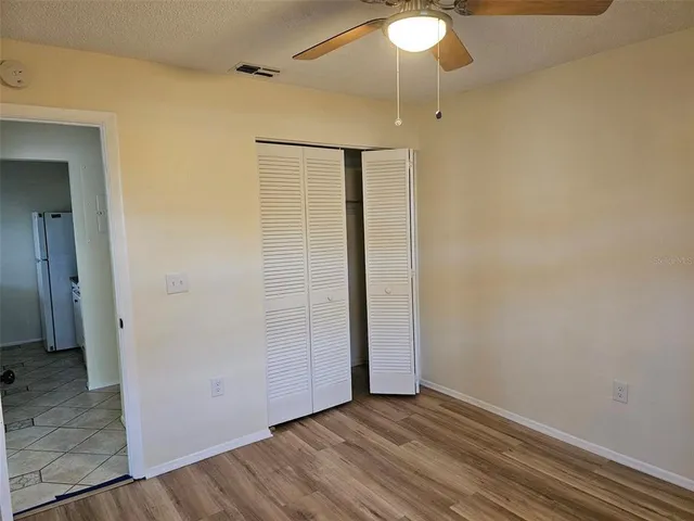 an empty room with wooden floor fan and windows