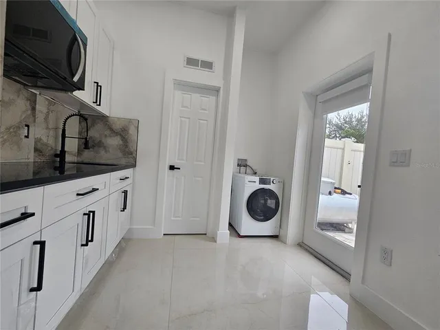 a view of a kitchen with a sink washer and dryer