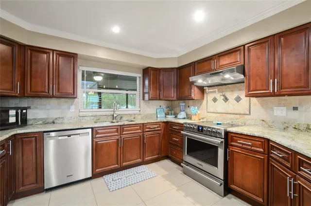 a kitchen with stainless steel appliances granite countertop wooden cabinets stove top oven and sink