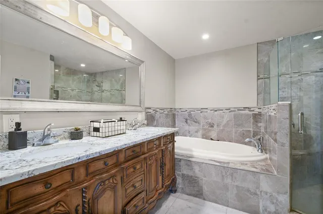 a bathroom with a granite countertop bathtub sink and mirror