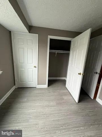a view of an empty room with wooden floor and a cabinet