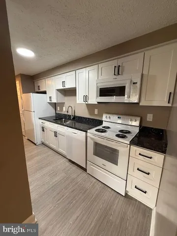a kitchen with granite countertop a sink a stove and cabinets