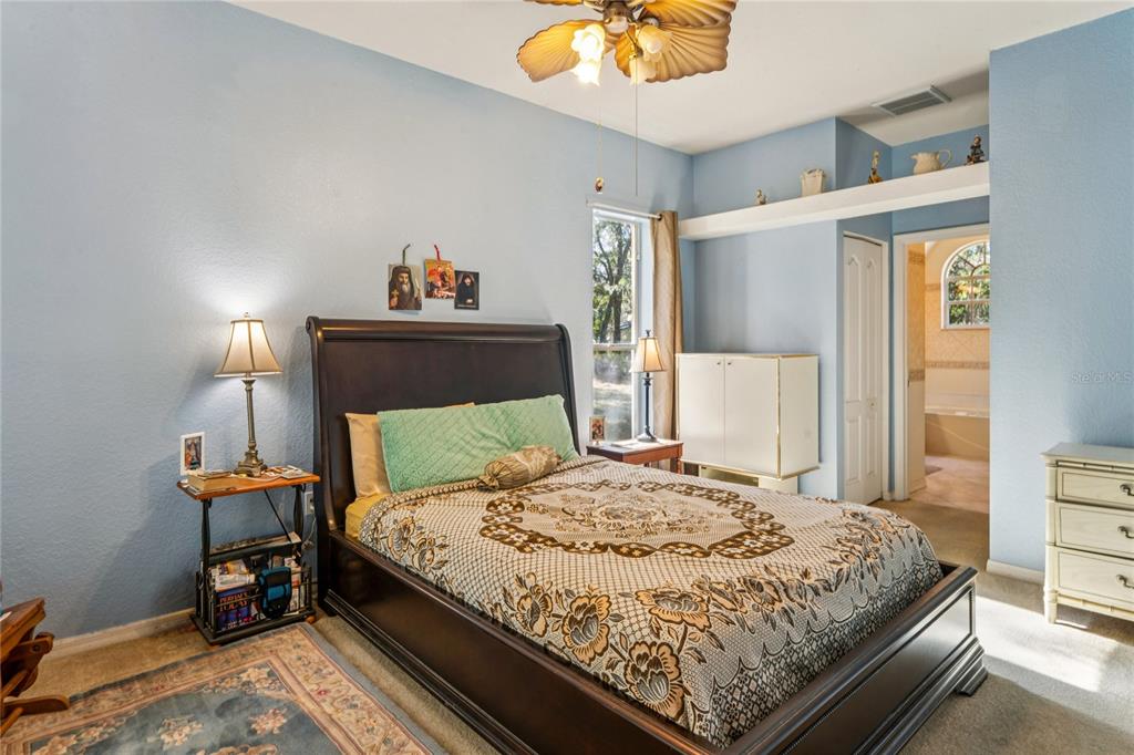 26861 Mondon Hill Road Brooksville, FL 34602 - Photo 17 of 51 a bedroom with a bed and a chandelier