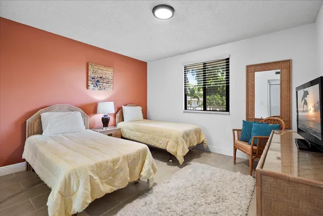 a bedroom with two beds and a large mirror next to a window