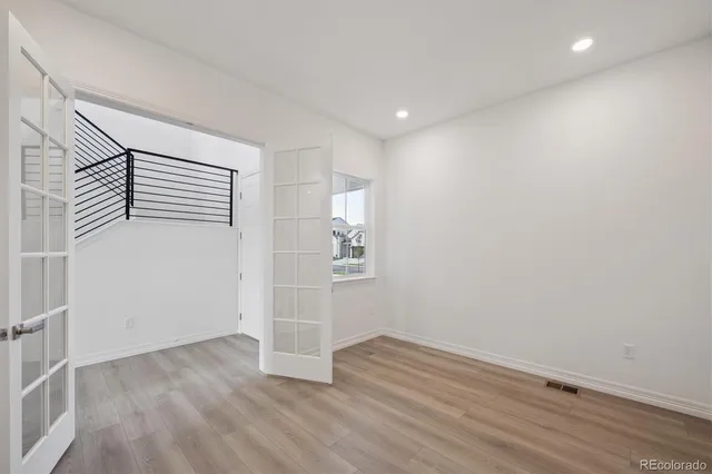 an empty room with wooden floor and windows