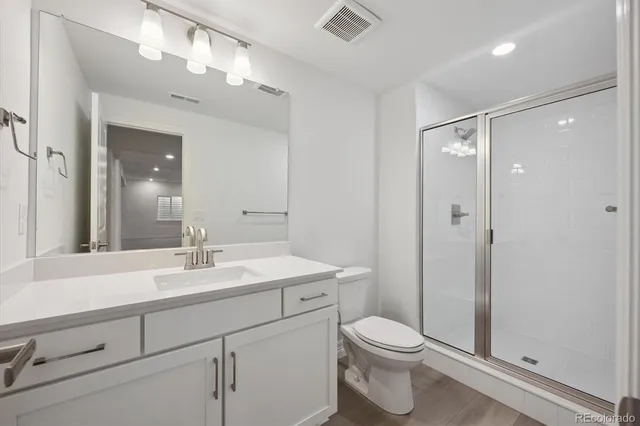 a bathroom with a sink a toilet a mirror and shower