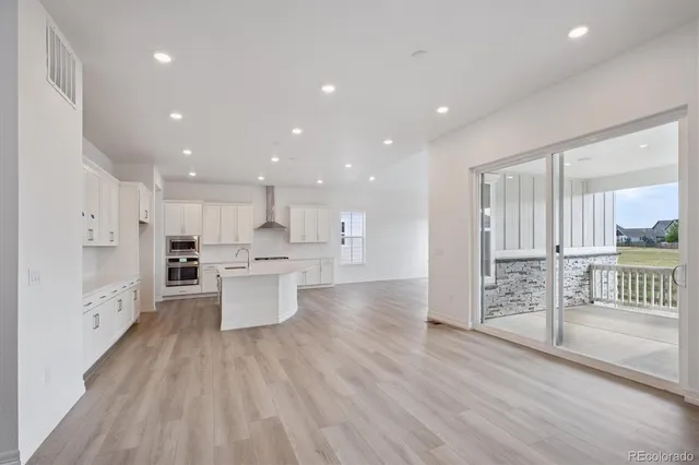 a large kitchen with stainless steel appliances kitchen island a large counter top and wooden floors