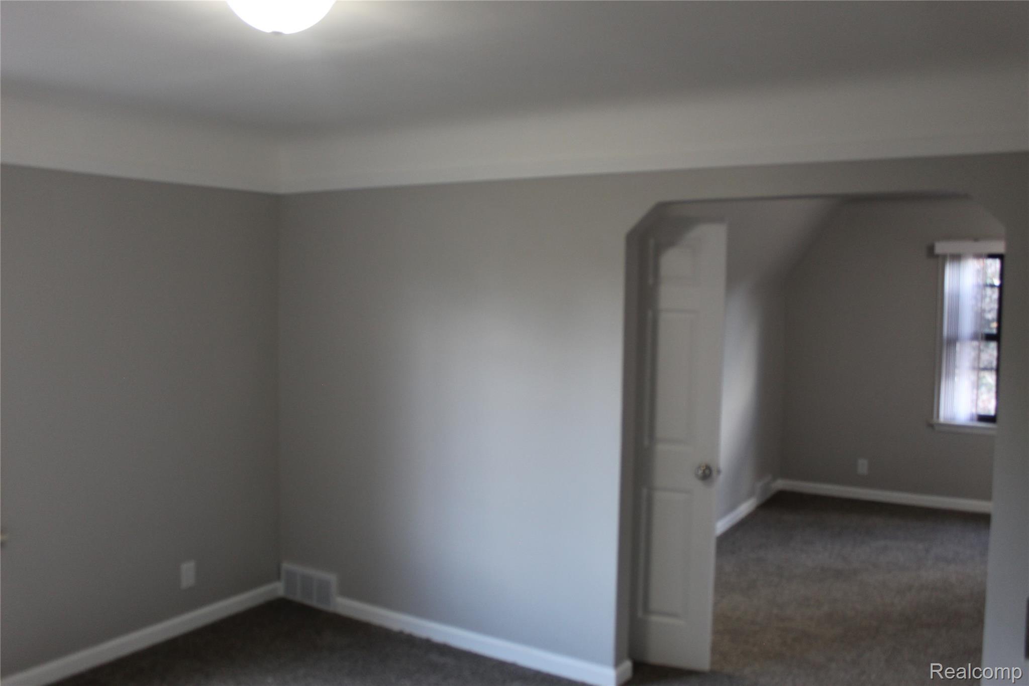 5543 Balfour Road Detroit, MI 48224 - Photo 49 of 54 Neutral gray wall paint with white trim, a flush-mount ceiling light, and dark carpeting