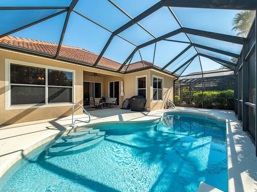7896 Founders Circle Naples, FL 34104 - Photo 12 of 12 a view of a swimming pool with dining table and chairs under an umbrella
