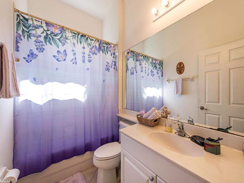 7896 Founders Circle Naples, FL 34104 - Photo 9 of 12 a bathroom with a sink a toilet and shower curtain