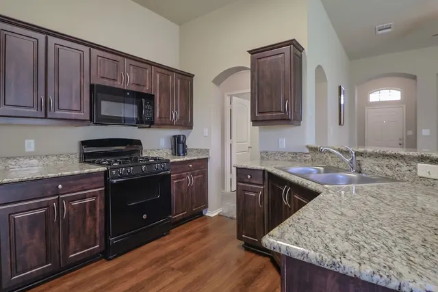 a kitchen with stainless steel appliances granite countertop wooden cabinets stove top oven and sink