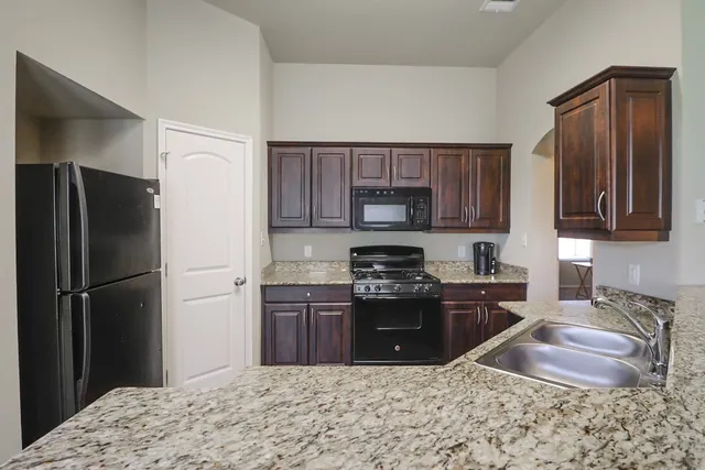 a kitchen with stainless steel appliances granite countertop a refrigerator stove and microwave