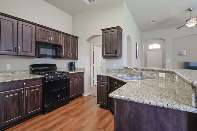 a kitchen with kitchen island granite countertop stainless steel appliances a stove sink and microwave