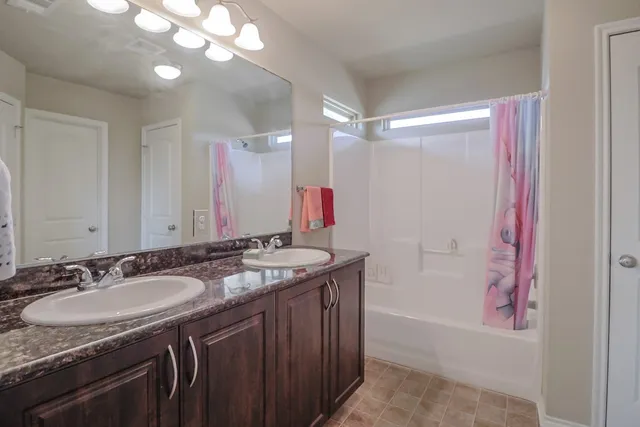 a bathroom with a granite countertop sink a mirror a vanity and a bathtub