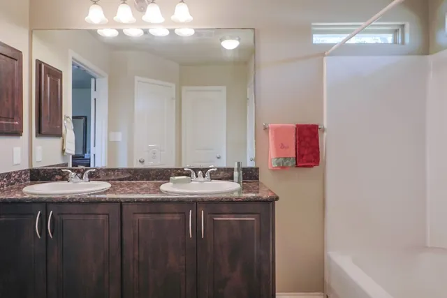 a bathroom with a granite countertop sink a large mirror and a bathtub