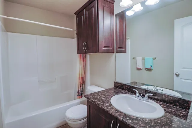 a bathroom with a granite countertop sink a toilet and shower