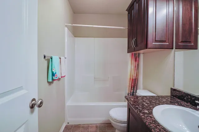 a bathroom with a granite countertop bathtub sink vanity mirror and toilet