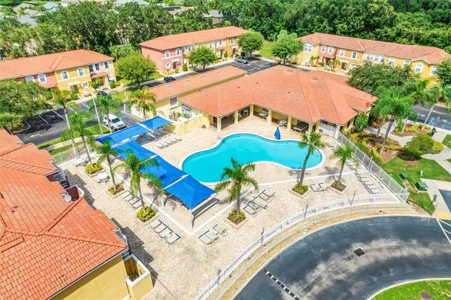 an aerial view of a house with swimming pool and large trees