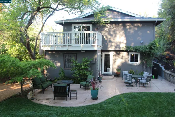 a view of a patio with table and chairs potted plants and large tree